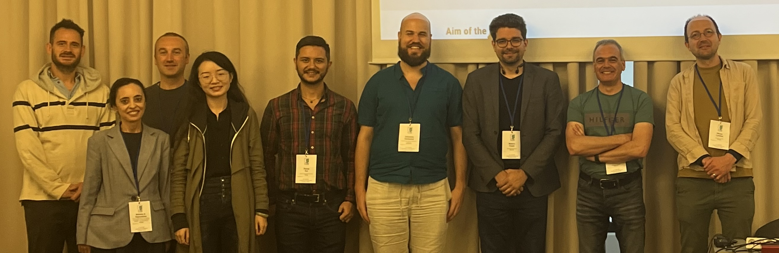 A group of men standing in front of a projector screen
Description automatically generated